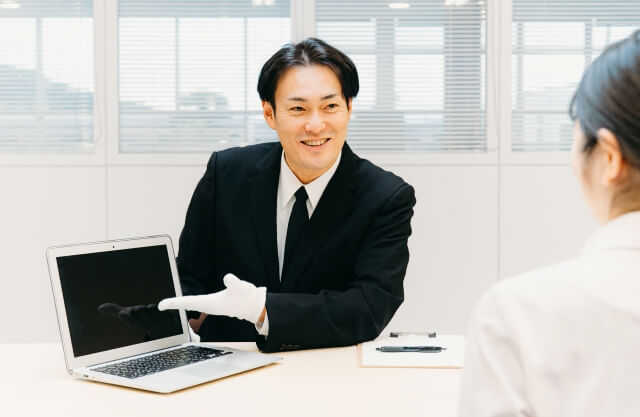 お客様にパソコンを示す買取業者