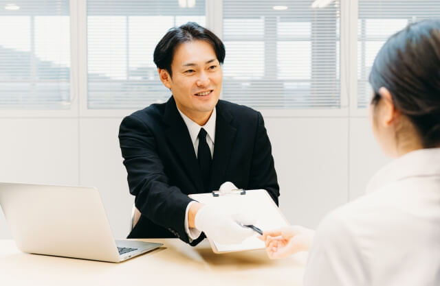 お客様にペンと書類を渡す買取業者